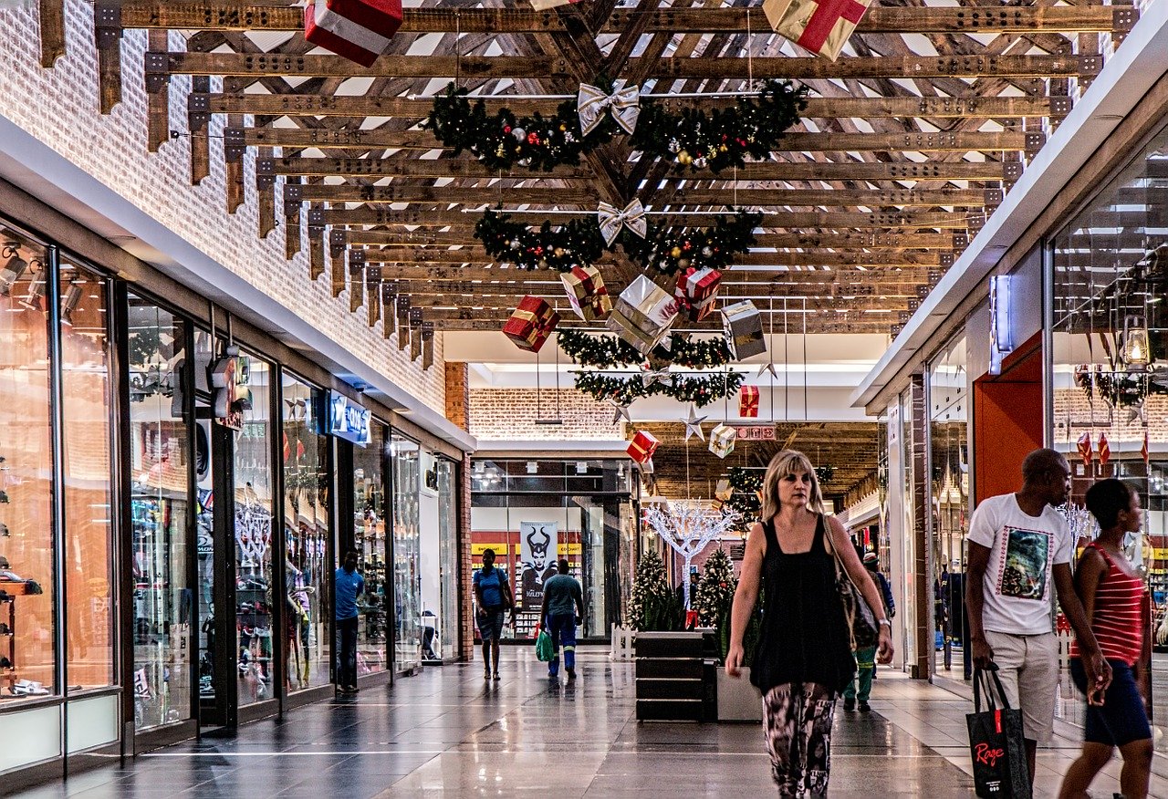 A woman walking down the aisle of an indoor mall.