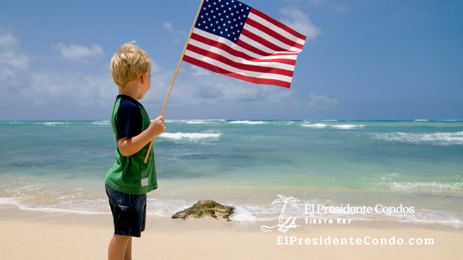 A boy holding an american flag on the beach
